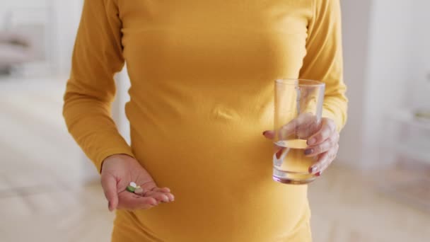 Prenatální doplňky. Těhotná žena drží pilulky a sklenici vody — Stock video