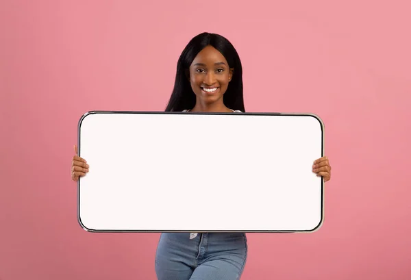 Vrolijke zwarte dame toont grote witte lege smartphone scherm — Stockfoto