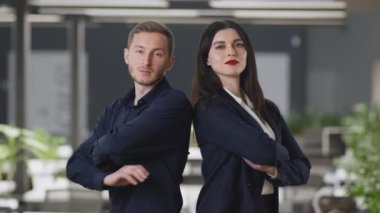 Profesyonel iş ekibi. Kendine güvenen erkek ve kadın ortaklar modern ofiste sırt sırta poz veriyorlar.