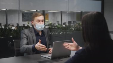 Yeni normal ve iş anlaşması. Yüzü maskeli bir iş adamı kadın müşteriyle ilgileniyor ama el sıkışmayın.