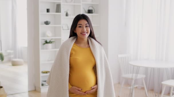 Όμορφη νεαρή Ασιάτισσα έγκυος γυναίκα που καλύπτεται με καρό απόσπαση στο εσωτερικό του σπιτιού — Αρχείο Βίντεο