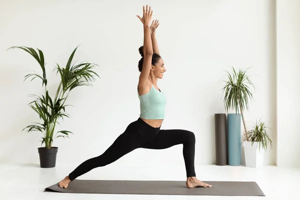 Sporty Young Woman Doing Yoga In Studio, Standing In Warrior 1 Pose — стокове фото