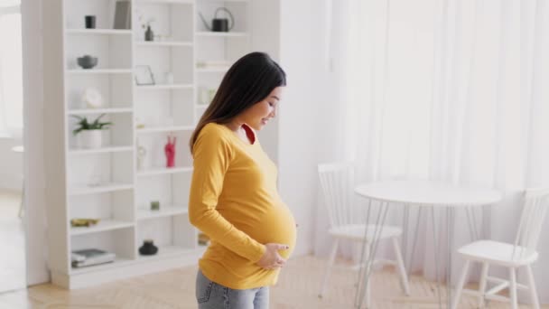 Счастливого времени беременности. Вид сбоку красивой беременной женщины, трогающей животик — стоковое видео