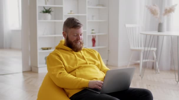 Baarded man freelancer met behulp van laptop typen werken online zitten binnen — Stockvideo