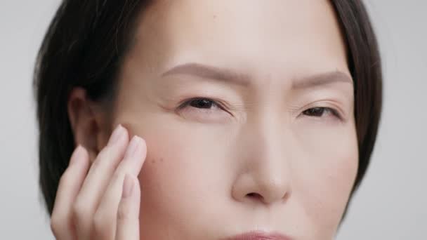 Покриття середньолітньої японської жінки доторкаючись крихти, сіре тло — стокове відео