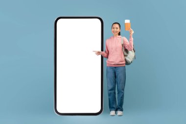 Heyecanlı Asyalı kadın internetten bilet ayırtıyor, akıllı telefon ve boş ekran.
