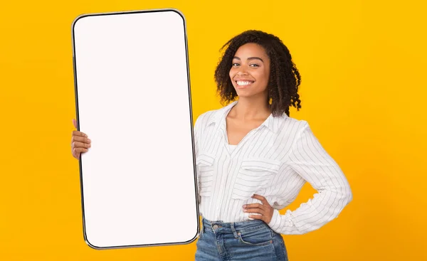 Veselý černošky dáma ukazuje velký bílý prázdný smartphone obrazovce — Stock fotografie