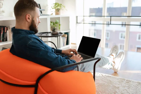 Ελεύθερος επαγγελματίας άνθρωπος χρησιμοποιώντας το lap-top με την άδεια οθόνη που κάθεται στο σπίτι — Φωτογραφία Αρχείου