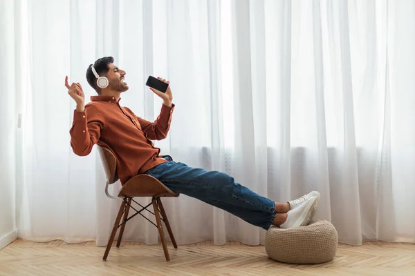 Homem árabe feliz usando celular usando fones de ouvido e cantando — Fotografia de Stock