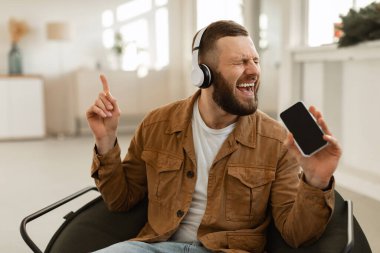Adam elinde akıllı telefon tutarak eğleniyor Evde müzik dinliyor