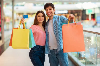 Eşler Kredi kartını ve alışveriş torbalarını alışveriş merkezinde gösteriyor