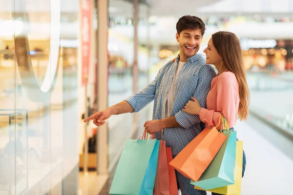 Çift alışverişi, erkek arkadaşının hipermarketteki dükkan vitrinini göstermesi.