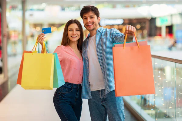 Esposos mostrando tarjetas de crédito y bolsas de compras en el centro comercial —  Fotos de Stock