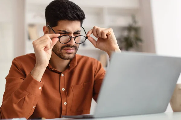 Confused Arab guy using laptop looking at screen — Stock Photo, Image
