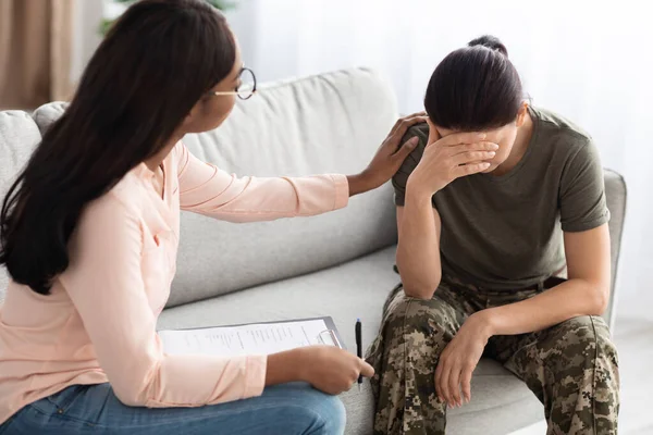 Nero psicologo signora confortante soldato donna in uniforme durante terapia sessione — Foto Stock