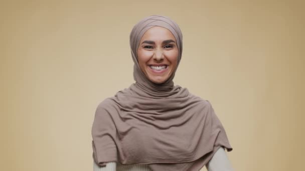 Победа и волнение. Студийный портрет молодой эмоциональной счастливой леди Среднего Востока в хиджабе, жестикулирующей ДА и танцующей — стоковое видео