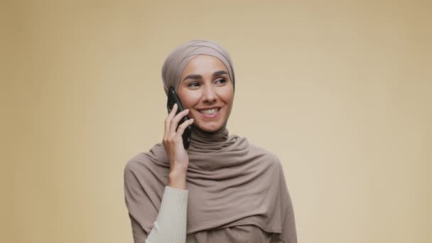 Modern communication concept. Young cheerful muslim woman wearing traditional hijab talking on cellphone — Stock Video