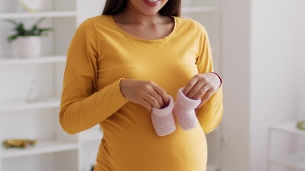 Moederschap Concept. Close-up van zwangere vrouw met kleine baby schoenen in de buurt van de buik — Stockvideo