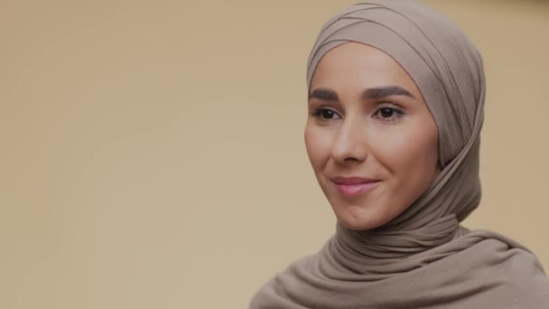 Poloprofilový portrét mladé mírumilovné muslimky v tradičním hidžábu dívající se stranou a jemně se usmívající, prázdný prostor — Stock video