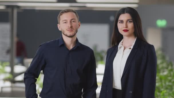 Jovem confiante homem e mulher parceiros de negócios sorrindo confiantemente para a câmera, posando com os braços cruzados no escritório moderno — Vídeo de Stock