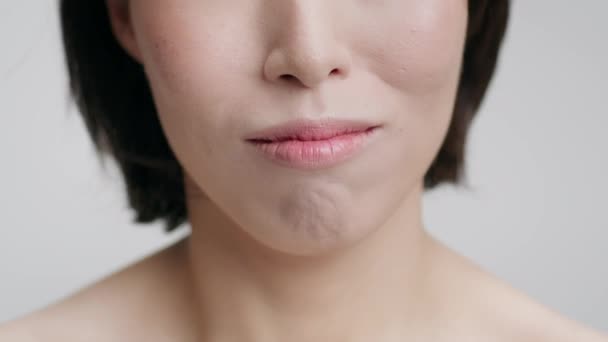 Primer plano de hembra asiática sonriendo mostrando dientes sobre fondo gris — Vídeos de Stock