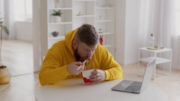 男自由职业者在家吃电脑附近的面条吃午饭 — 图库视频影像