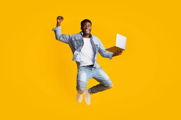 Alegre afro-americano cara segurando laptop e pulando — Fotografia de Stock