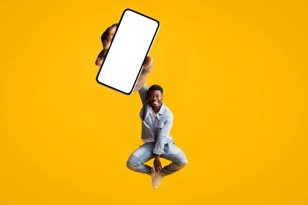 Θετικός κομψός νεαρός μαύρος άνδρας που δείχνει την τελευταία εφαρμογή για κινητά — Φωτογραφία Αρχείου