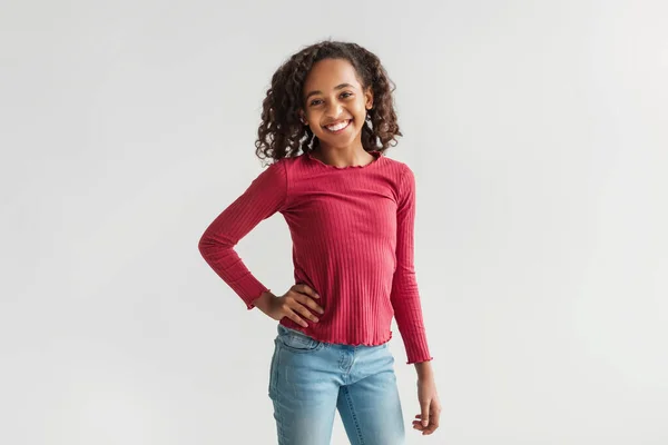 Vrolijke Afro-Amerikaanse tiener meisje poseren staande over grijze achtergrond — Stockfoto