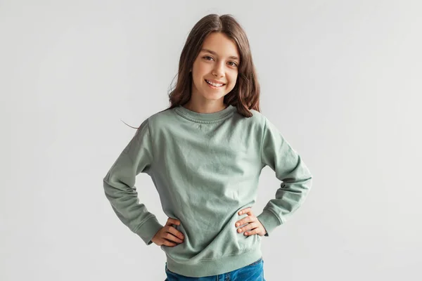 Alegre chica preadolescente posando con las manos en las caderas, fondo gris — Foto de Stock