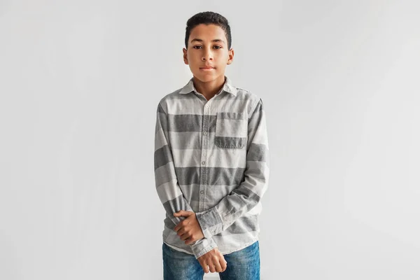 Gravierende schwarze Preteen Boy Blick auf Kamera über grauen Hintergrund — Stockfoto