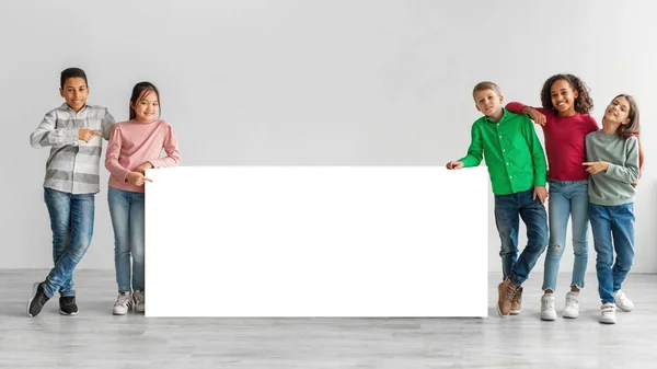 Felice Diversi bambini in piedi vicino a bordo bianco su sfondo grigio — Foto Stock