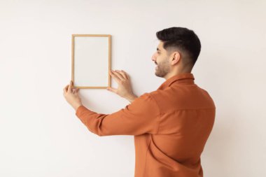 Duvara resim çerçevesi asan genç adam.