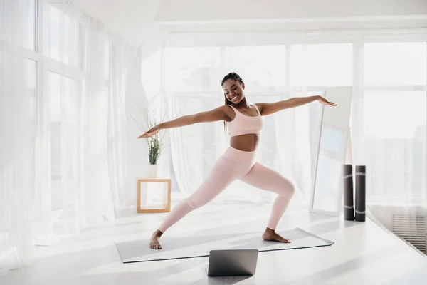 Neşeli fit genç zenci kadın evde yoga yapıyor, savaşçı pozunda duruyor, boşluğu kopyalıyor. — Stok fotoğraf