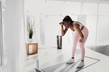 Alnını dizüstü bilgisayarın yanına silen yorgun genç siyahi kadın evde online eğitimden, boş alandan bıkmış.