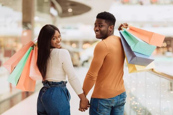 Retrato de feliz pareja negra mirando hacia atrás con bolsas de compras —  Fotos de Stock