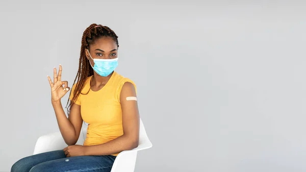 Recomiendo la vacuna contra el coronavirus. Joven dama negra con máscara facial vacunada contra el virus covid mostrando un gesto aceptable —  Fotos de Stock