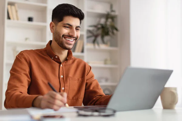 Portret uśmiechniętego Araba korzystającego z laptopa i piszącego — Zdjęcie stockowe