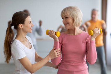 Yaşlılardan oluşan çok ırklı bir gruba yardım eden fitness eğitmeni