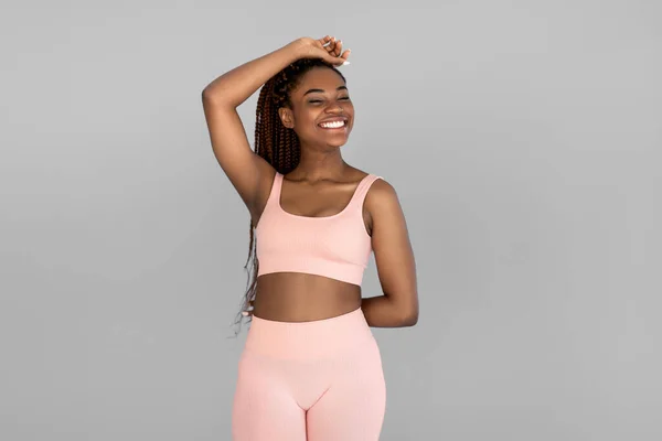 Retrato de la joven mujer negra feliz en traje deportivo posando y sonriendo sobre fondo gris estudio — Foto de Stock