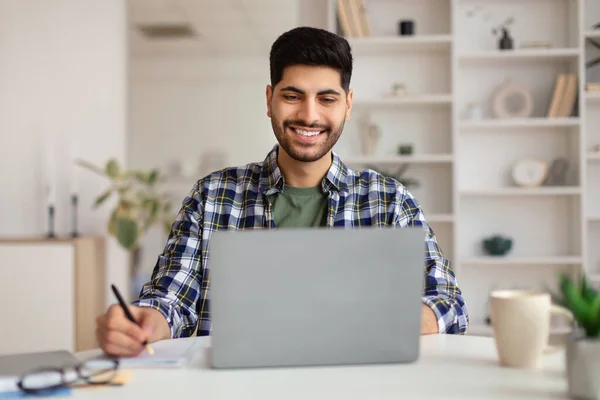 Porträt eines lächelnden arabischen Mannes, der Laptop benutzt und schreibt — Stockfoto