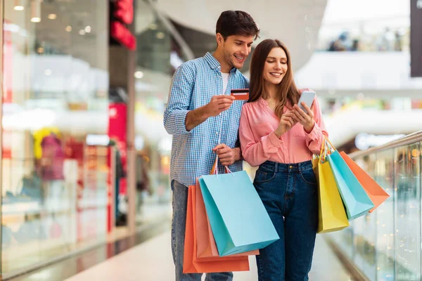 Casal feliz compras usando Smartphone e cartão de crédito no shopping — Fotografia de Stock