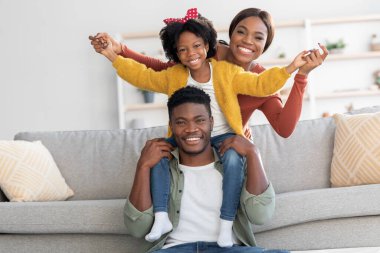 Üç kişilik neşeli siyah aile portresi evde birlikte eğleniyor.