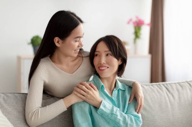 Genç ve güzel Asyalı bir kadının portresi. Evde olgun annesine sarılıyor. Aile mutluluğu ve dostça ilişkiler