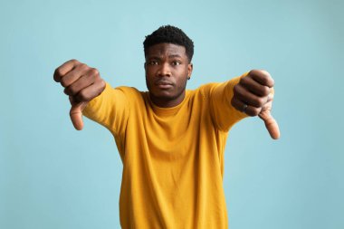 Üzgün Afro-Amerikan adam mavi üzerine başparmak gösteriyor.