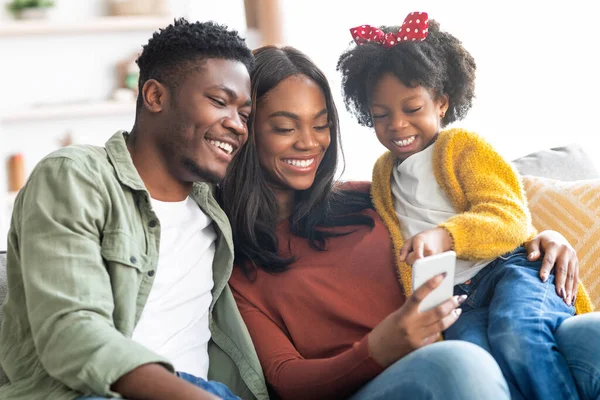 Technologieën voor vrije tijd. zwart familie van drie met behulp van smartphone thuis samen — Stockfoto