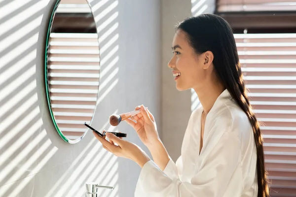 Perfil vista de mulher coreana bonita aplicando maquiagem no banheiro — Fotografia de Stock
