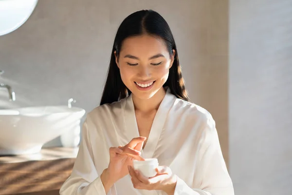 Sorrindo jovem asiático senhora segurando jar com beleza produto — Fotografia de Stock