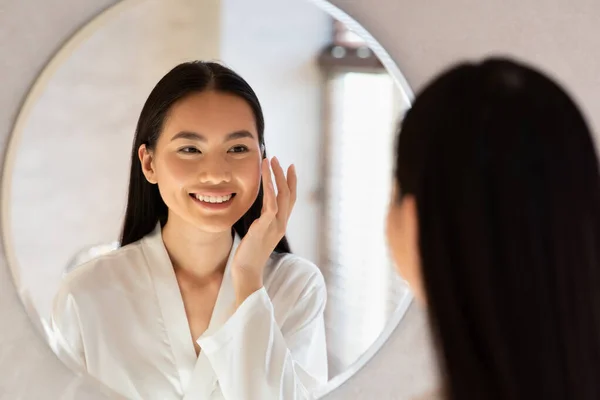 Happy beautiful korean lady using moisturising face cream — Stok Foto