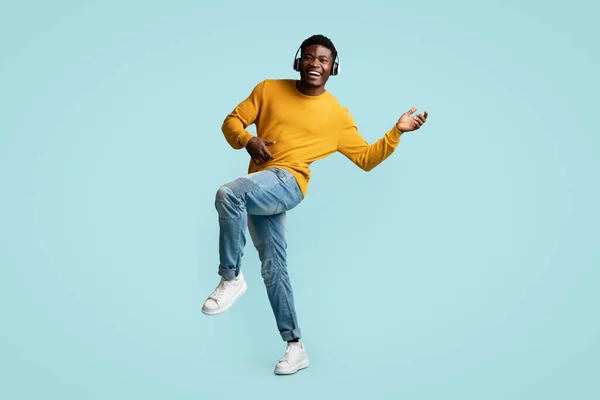 Chico negro joven despreocupado con auriculares inalámbricos bailando —  Fotos de Stock